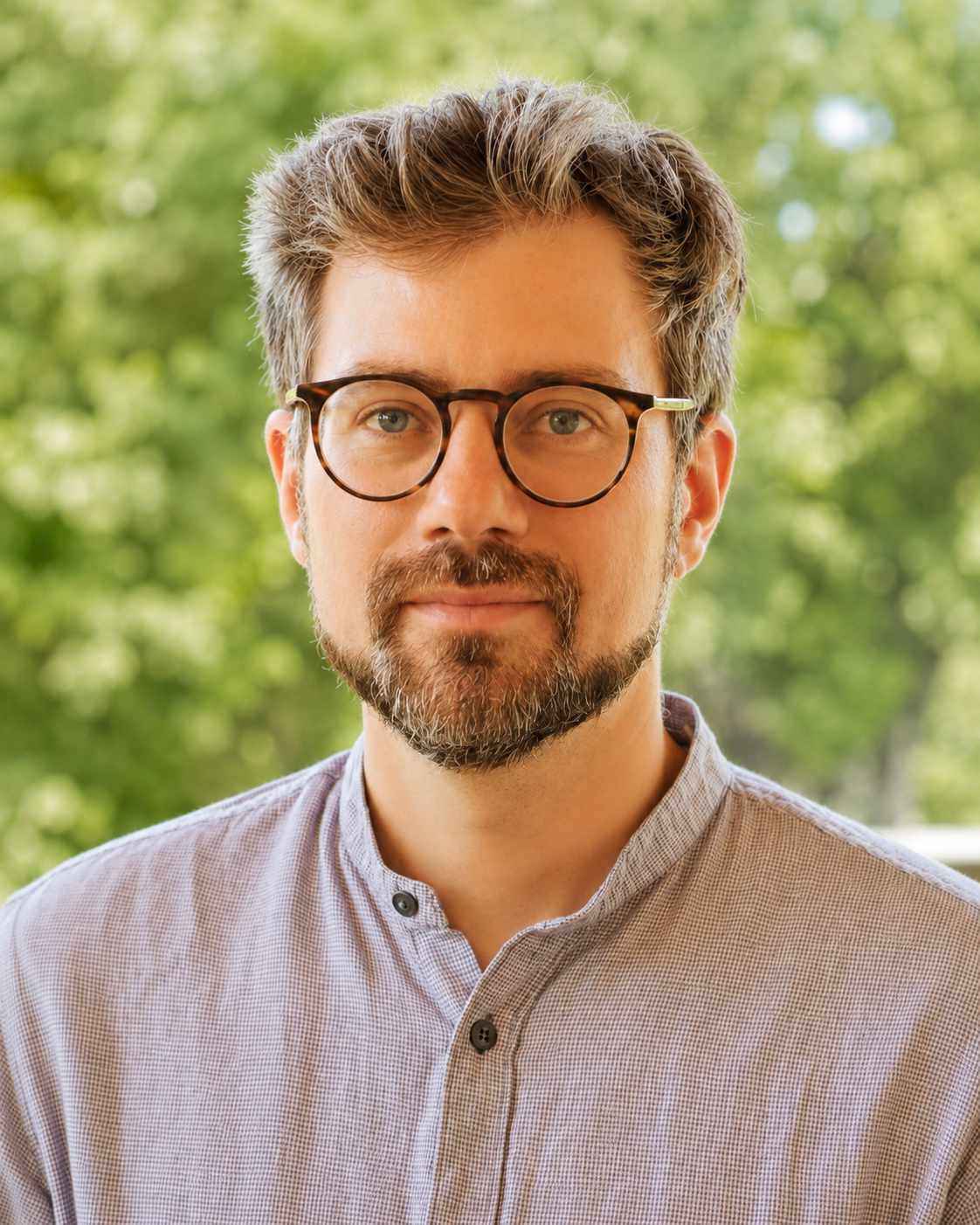 Jannis Seeberger mit Brille vor sommerlichem Grün